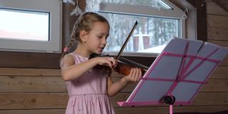 可爱的小女孩在阁楼练习小提琴
