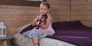 一个白人小女孩在家里拉小提琴