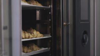 在一家商业厨房里，牛角面包在离开烤箱后被放在托盘里供顾客吃早餐视频素材模板下载