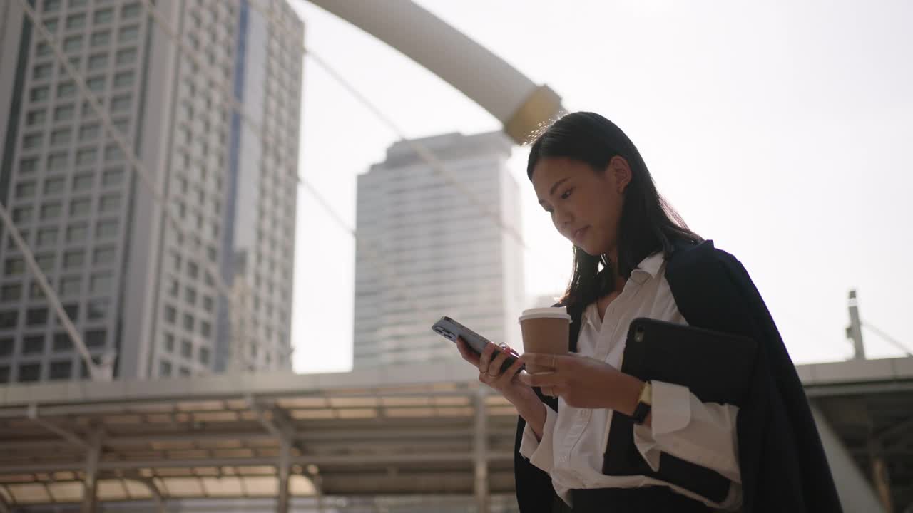 年轻的女商人一边走在街上一边发短信