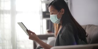 生病的年轻亚洲妇女与她的医生在数字平板电脑在家里交谈