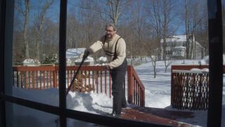 一名50岁的白人男子在清理冬天降雪后留下的门廊。视频素材模板下载