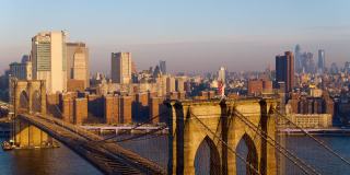近距离鸟瞰布鲁克林大桥塔顶飘扬的美国国旗，以东河对岸的曼哈顿天际线为背景。用静态摄像机拍摄无人机视频。
