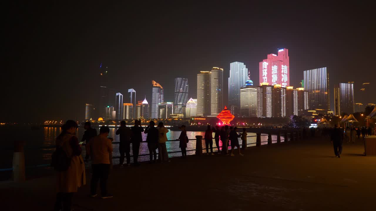 夜间灯光下，著名的青岛城市展示拥挤的步行街全景4k中国