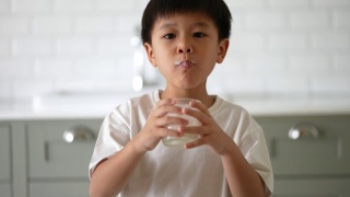 亚洲小孩早餐喝一杯牛奶。健康早餐的概念视频素材模板下载