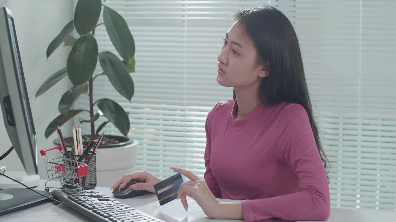 亚洲女性在家里用信用卡在电脑上购物