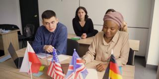 国外学校私学女生。老师用笔记本电脑讲解母语语法。和导师一起准备考试。前面是英国、英国、德国和波兰的国旗。