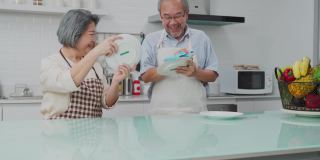 亚洲年轻的家庭主妇捻着湿抹布清洁厨房柜台。为了卫生和健康，老婆婆和男人在家做饭后在桌子和盘子上擦布。