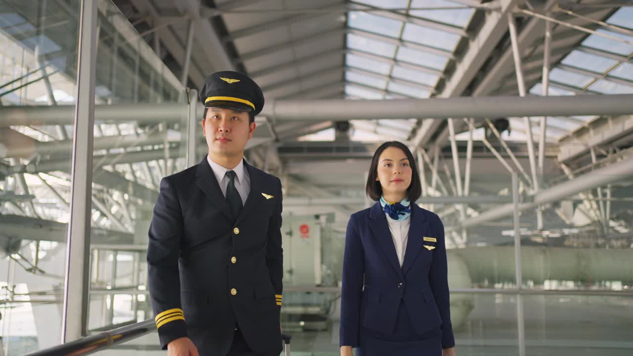 亚洲客机的飞行员和空姐在机场候机楼边走边聊，面带微笑，幸福地走向飞机。商务舱乘务人员或空姐和飞行员的职业概念。