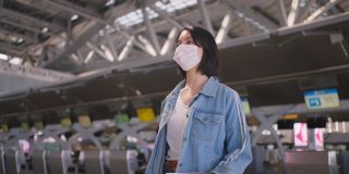 新冠肺炎疫情期间，佩戴口罩的女乘客在机场航站楼走向登机口，以防止感染新冠肺炎。飞机运输的新常态生活理念。