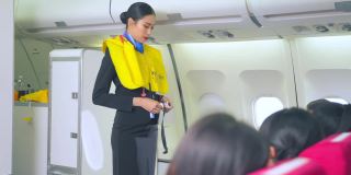 亚洲空乘人员在飞机起飞前解释并展示救生衣使用的安全演示。机组人员在飞行过程中为乘客安全做了演示。