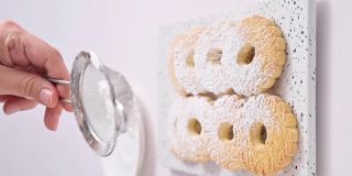 Canestrelli，传统利古里亚洋甘菊形状的糖粉饼干。来自意大利南部的节日烘焙食品，卷面。那女人把饼干撒在蛋糕上。垂直视频，用于社交网络。