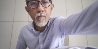 亚洲华人资深男教授家教老师听他的成人学生使用笔记本电脑在家里工作