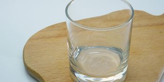 将新鲜的酸乳酒倒入玻璃杯中，一个木制托盘上的牛奶饮料，一个开胃的酸奶在玻璃杯中的特写镜头。