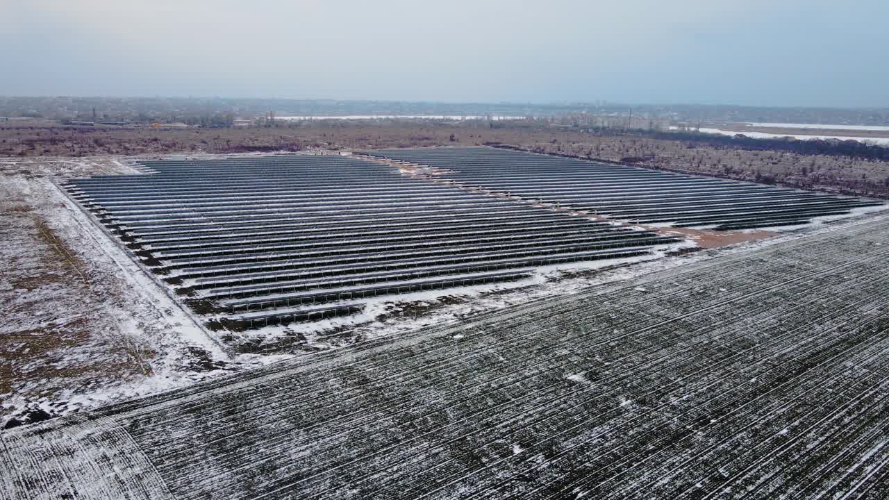 新太阳能农场的鸟瞰图，在雪地上站成一排现代光伏板