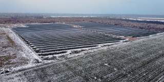 新太阳能农场的鸟瞰图，在雪地上站成一排现代光伏板