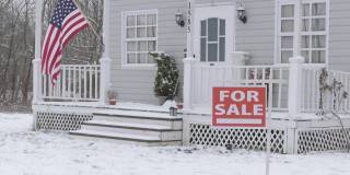 在隆冬季节，在被雪覆盖的院子里，大型独栋房屋前的房产标识正在出售аnd下雪了