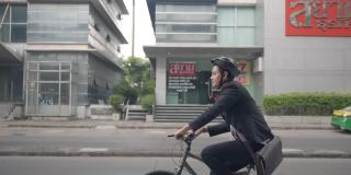 一名西装革履的亚洲商人正骑着自行车在城市的街道上上班。生态交通的概念。