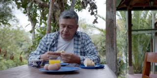 一个成熟的男人独自在乡村的家中吃早餐，欣赏着乡村的景色