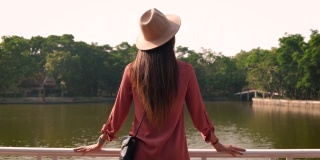 后视图的亚洲女性游客步行看到一个湖在公园。健康的生活方式。