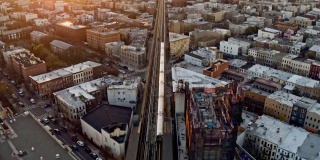 日落时分，一列火车正穿过纽约布鲁克林的住宅区。无人机视频与向前和倾斜加速摄像机运动。