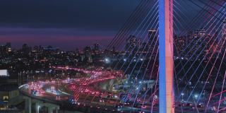 夜深时分，科修斯科大桥上的车流不断变换着颜色，背景是曼哈顿和布鲁克林的远处景色。航拍视频与平移摄像机运动。