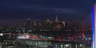 夜深时分，科修斯科大桥上的车流不断变换着颜色，背景是曼哈顿和布鲁克林的远处景色。航拍视频与宽平移摄像机运动。
