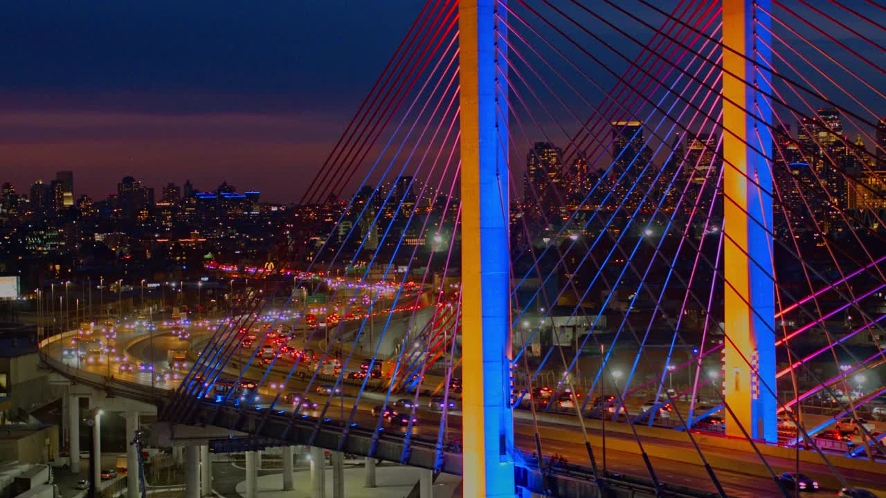 夜深人静的科修斯科大桥(Kosciuszko Bridge)灯火通明，背景是曼哈顿和布鲁克林的远处景色。航拍视频与长向后平移摄像机运动。