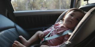 可爱的亚洲幼童女孩坐在汽车座椅上，感觉困倦，而与家人旅行。