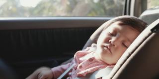 慢动作可爱的亚洲学步女孩坐在汽车座椅和睡觉，而与家人旅行。