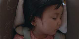 近距离观察可爱的亚洲蹒跚学步的女孩坐在汽车座椅和睡觉，而与家人旅行。