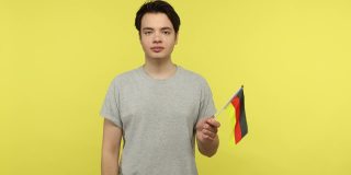积极的年轻人挥舞着德国国旗，看着镜头露齿微笑