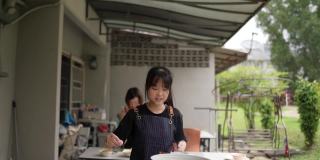 亚裔华人母亲和女儿在后院厨房准备食物。女儿在向母亲学习