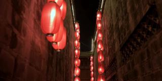晚上走向古庙狭窄走廊墙间的木阳台。点燃了红灯笼，四处悬挂着照明灯。传统装饰，节日庆典。