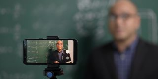 印度年轻教师男子通过智能手机进行在线视频会议直播。亚洲数学教师在线授课，供学生在线学习。