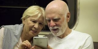 家人一起享受假期。老年夫妇乘地铁出行用手机浏览