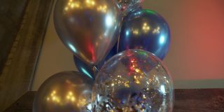 生日聚会上气球的慢动作背景。蓝色，红色，粉色，黄色，绿色的气球在晚会上轻音乐在夜总会的灯光。晚会的概念。节日的配件。
