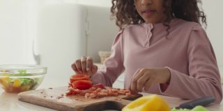 非洲裔美国小女孩试着切西红柿，皱着眉头，感觉恶心的味道，慢镜头
