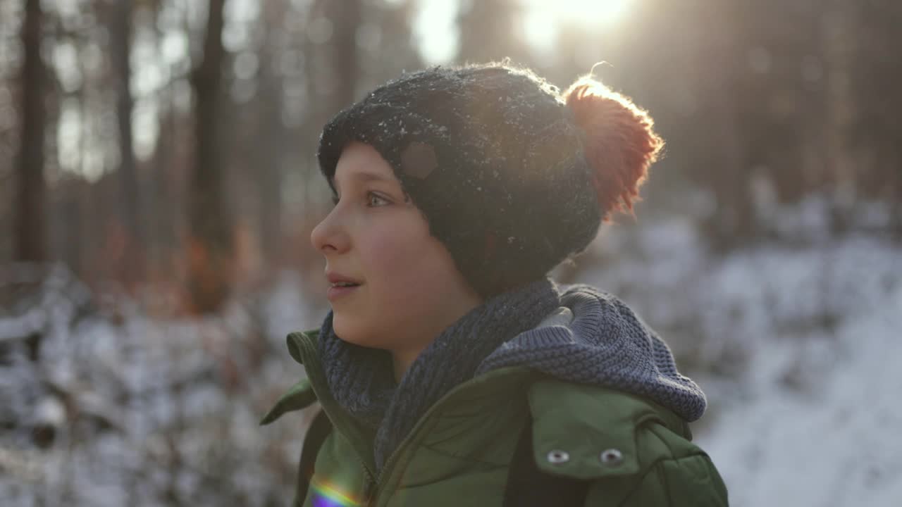 小男孩在美丽的冬季森林里徒步旅行的肖像。