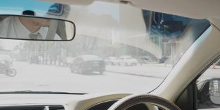 人调整汽车后视镜。特写的亚洲人穿着正装调整镜子前驾驶他的汽车