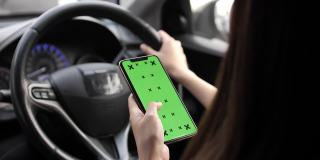 手持绿色空白屏幕的智能手机在电动汽车中寻找方向