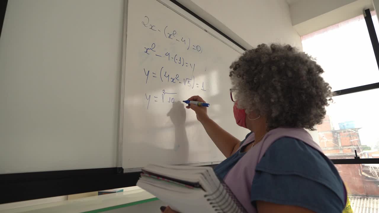 老师在黑板上写字，戴着口罩