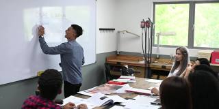 亚裔马来男讲师在教室里用白板给他的学生讲授珠宝设计课程