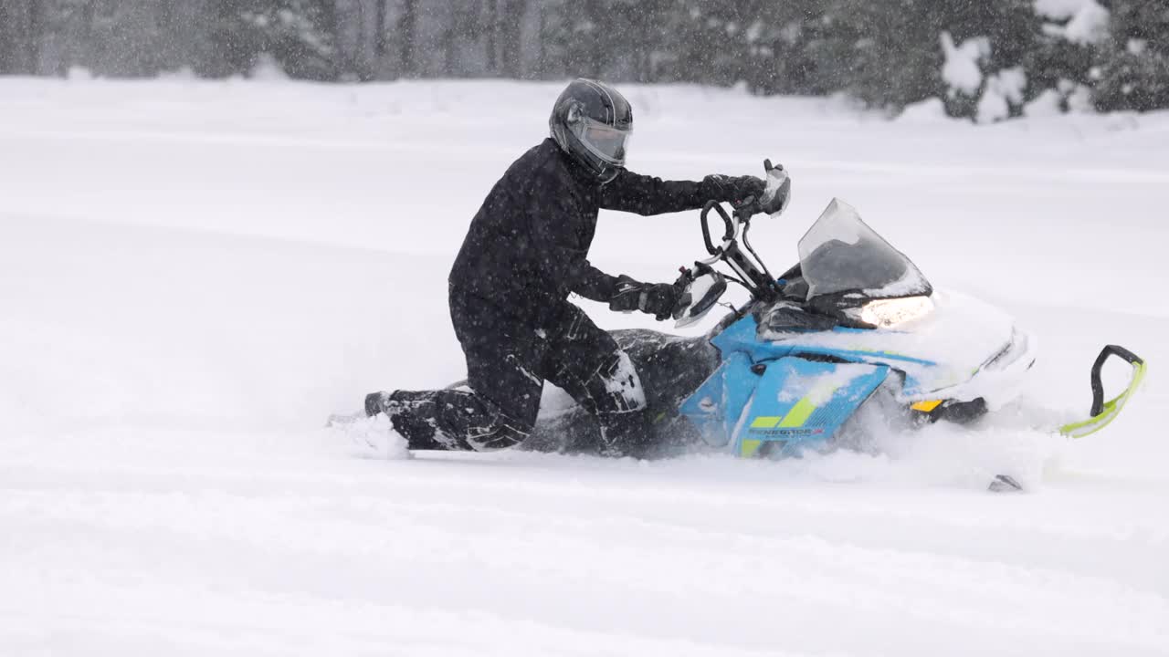 一个男人开着雪地摩托在粉末雪地里超速行驶的慢动作镜头