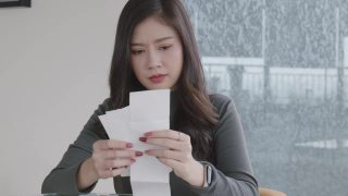 20 ~ 30岁的亚裔女性在家庭办公室工作和计算财务数据。视频素材模板下载