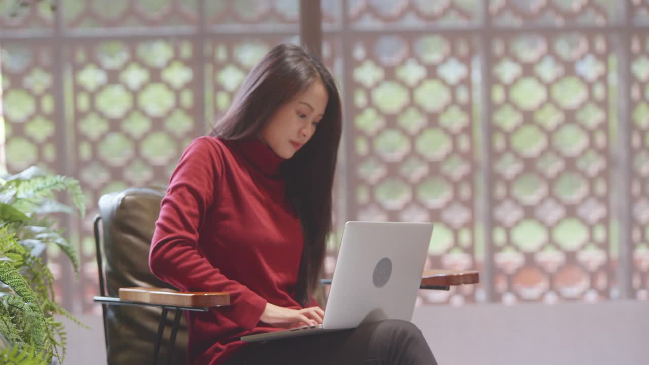亚洲商务女性，20-30岁，穿着休闲服装在咖啡店使用电脑