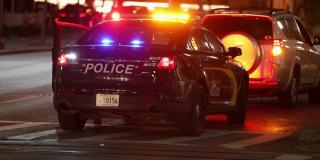 巴尔的摩城市街道和夜间警车灯。一名警察在公交专线上拦截了一辆不明车辆。马里兰