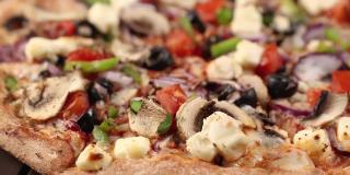 整个新鲜的圆形披萨，鸡肉，蔬菜，蘑菇和奶酪，在一个木制的棕色桌子上旋转。披萨店的美味快餐背景