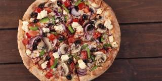 整个新鲜的圆披萨，鸡肉，蔬菜，蘑菇和奶酪在木制的棕色桌子上旋转。美味的快餐背景在披萨店俯视图，拷贝空间