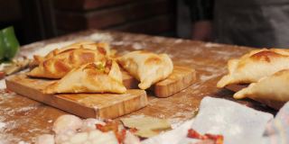 南美食物:脆炸肉馅肉馅卷饼，放在白色的托盘上，白色的木头背景上，配有厨房抹布